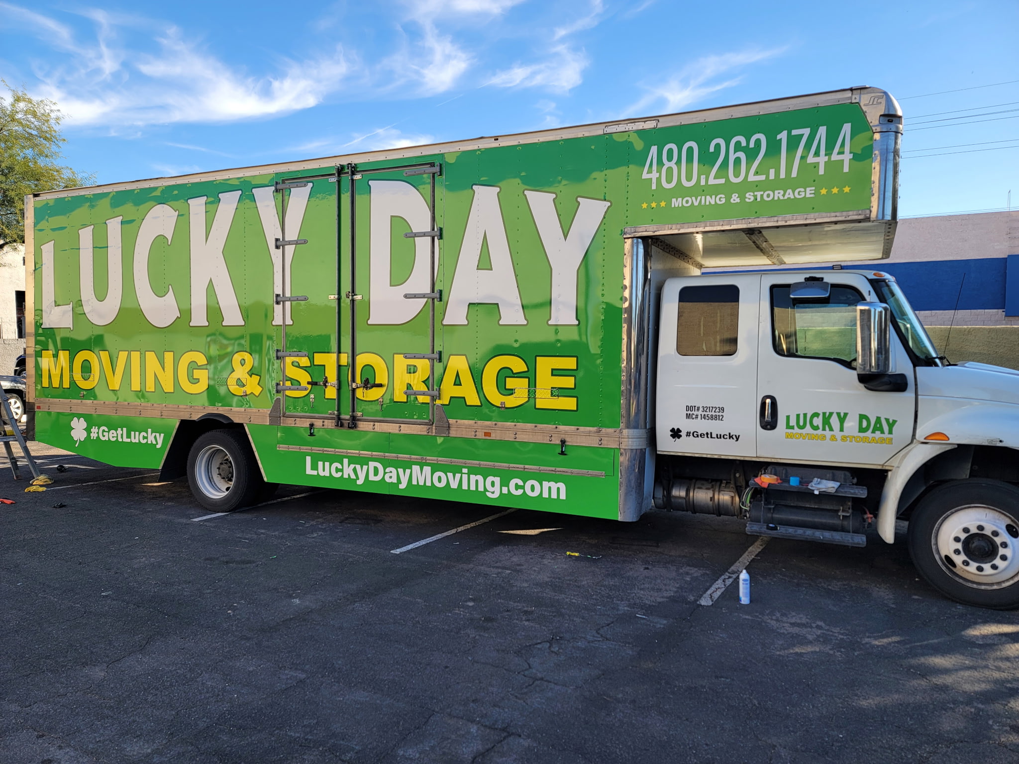 Lucky Day Moving crew loading boxes onto a clean moving truck — safety gear visible, professional East Valley movers