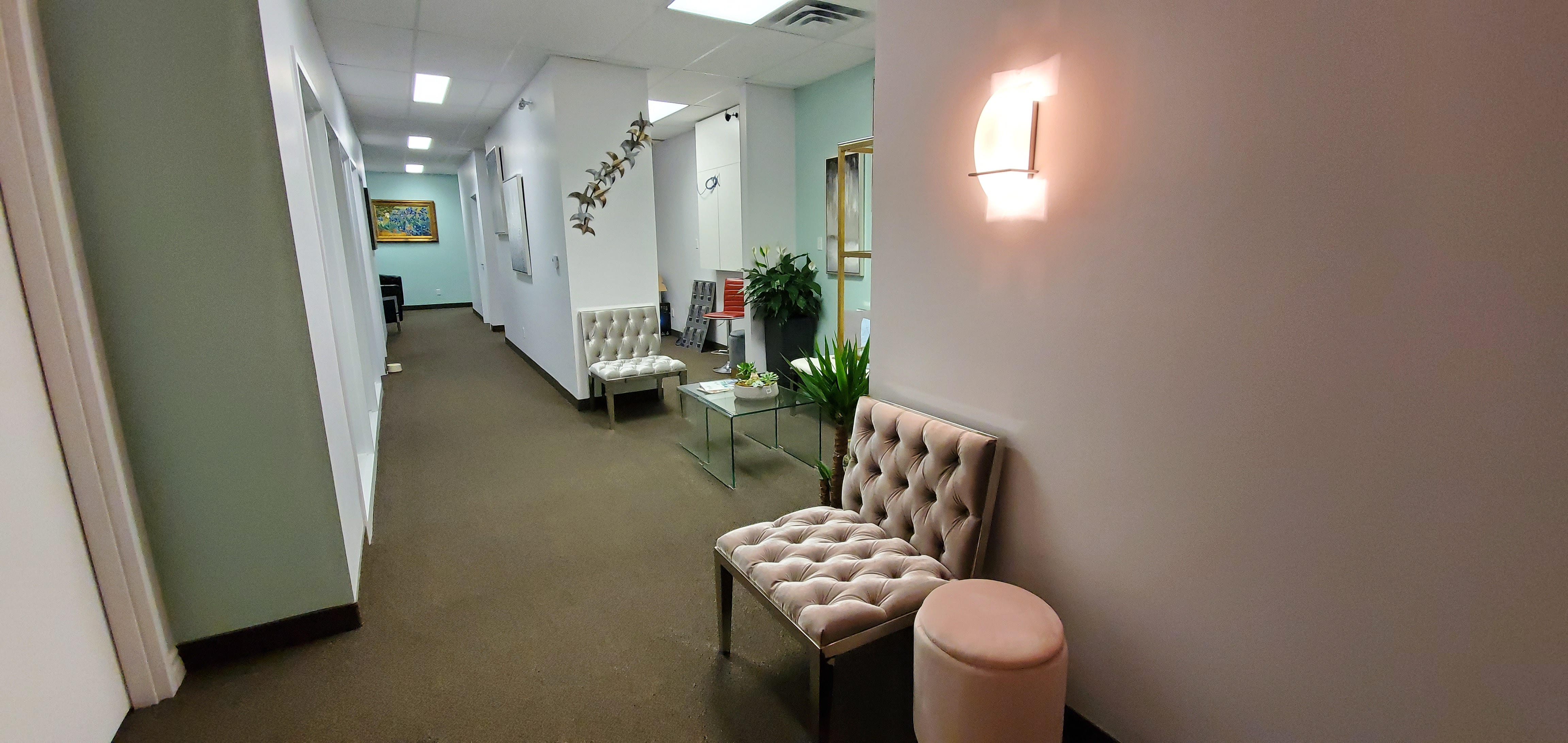 Modern hallway with seating, plants, and artwork on the walls.