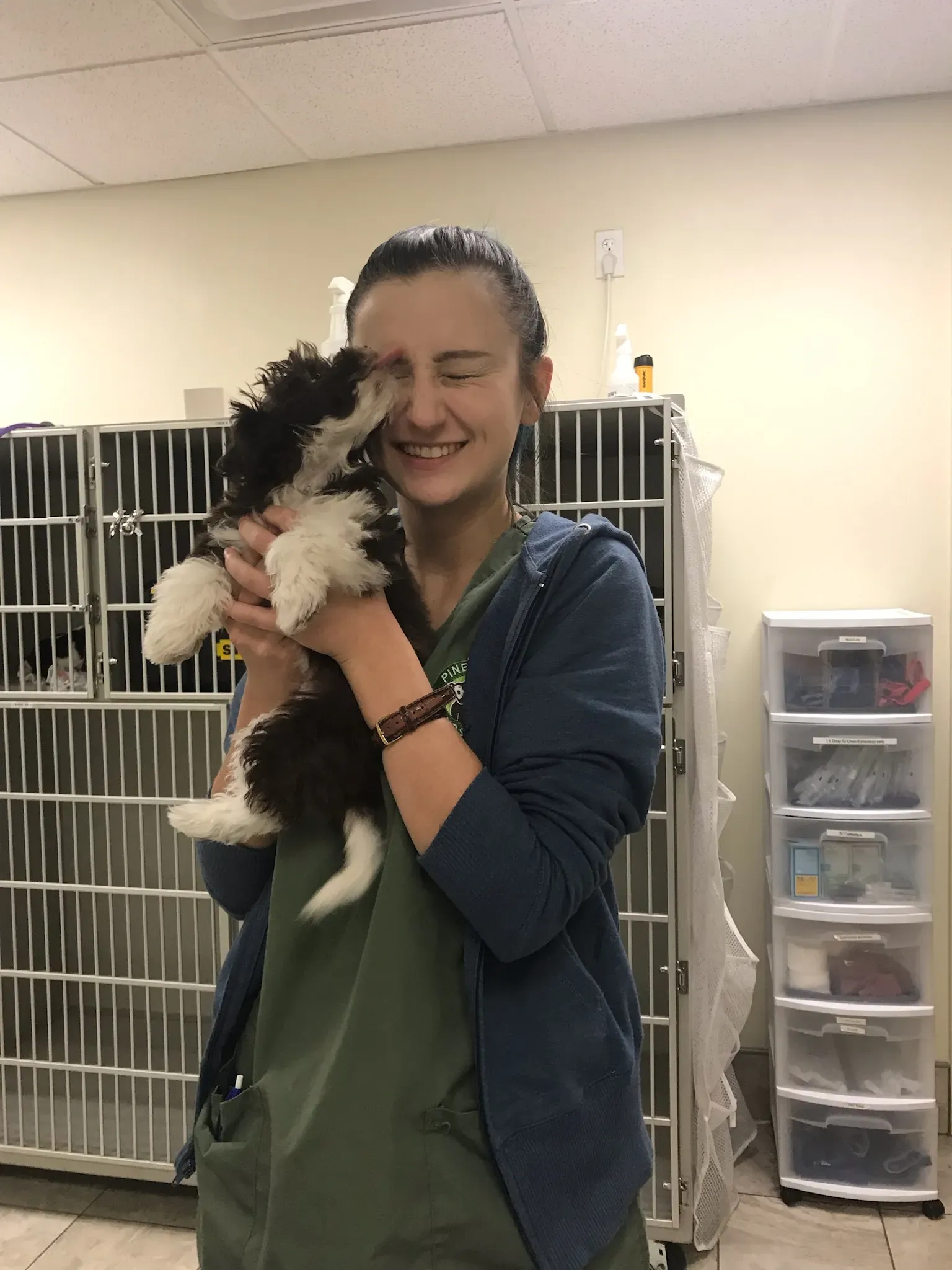 Veterinary technician smiling while holding a small puppy in a clinic setting