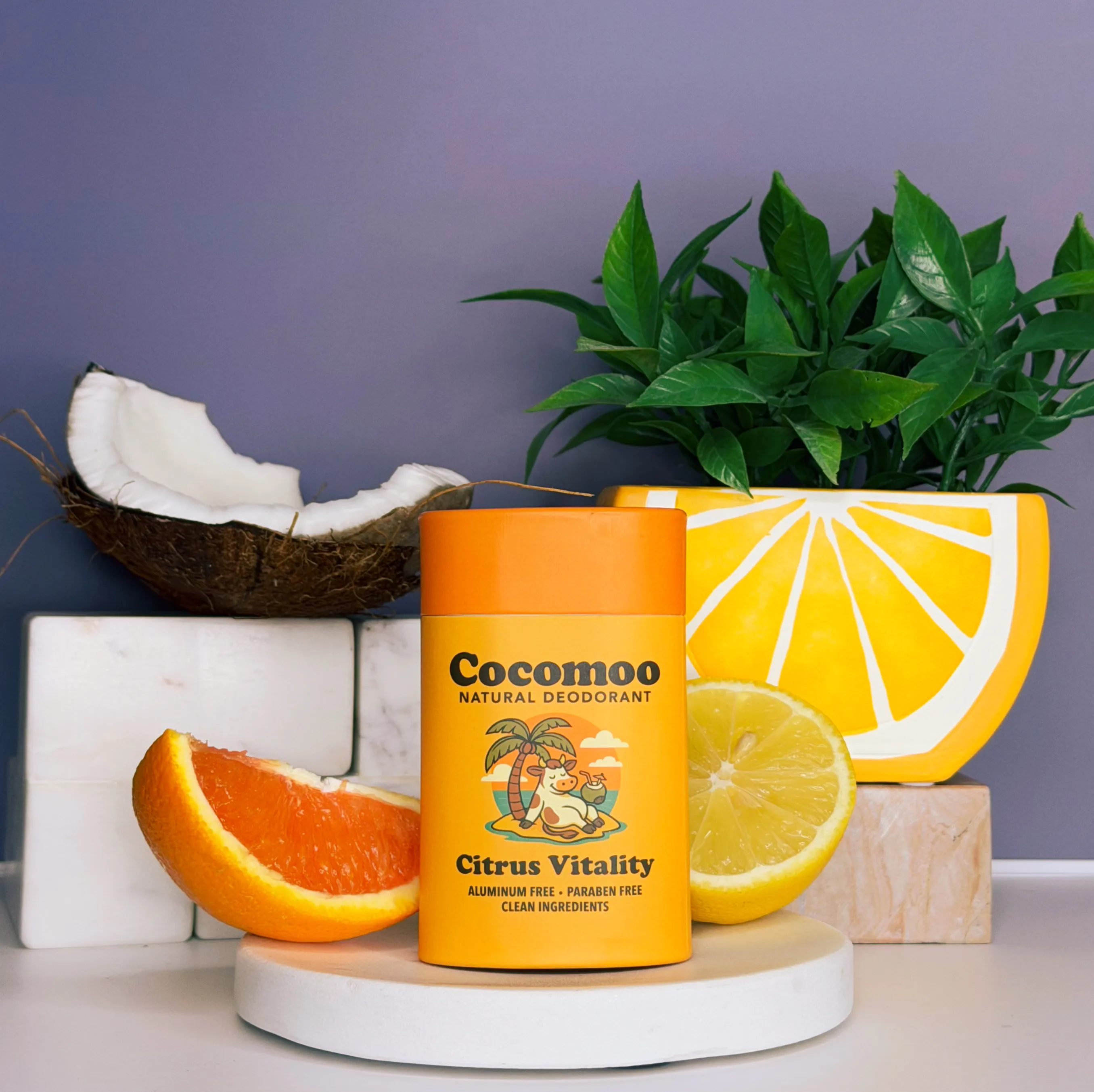 Natural deodorant on a white pedestal, surrounded by citrus fruits and foliage.