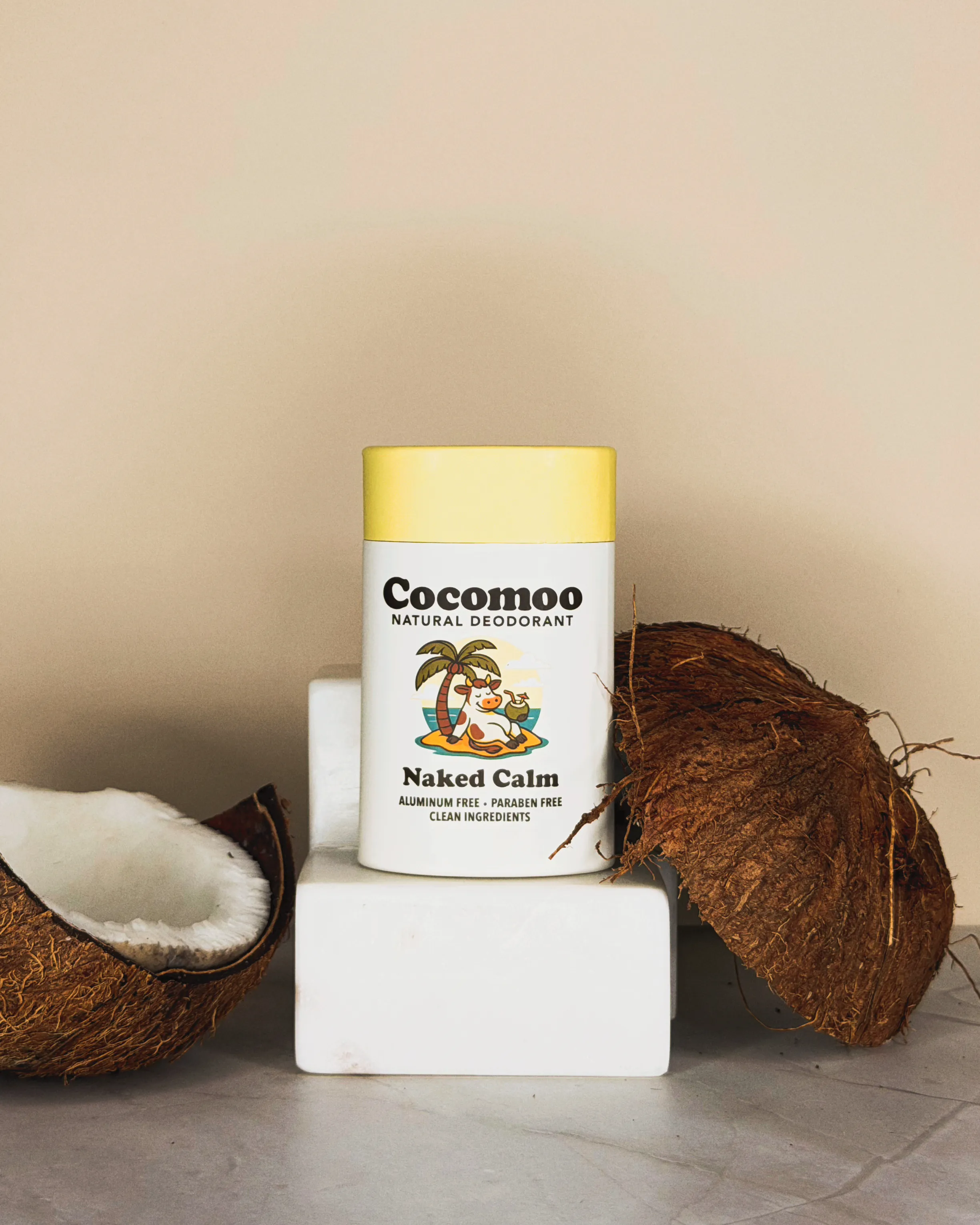Naked Calm natural deodorant with coconut shells on a marble surface.
