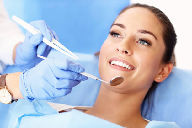 Woman smiling during a dental check-up with a dentist using instruments