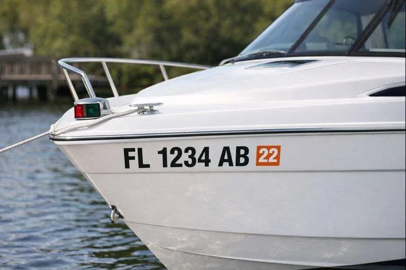 Bow of a white motorboat with registration number on the water