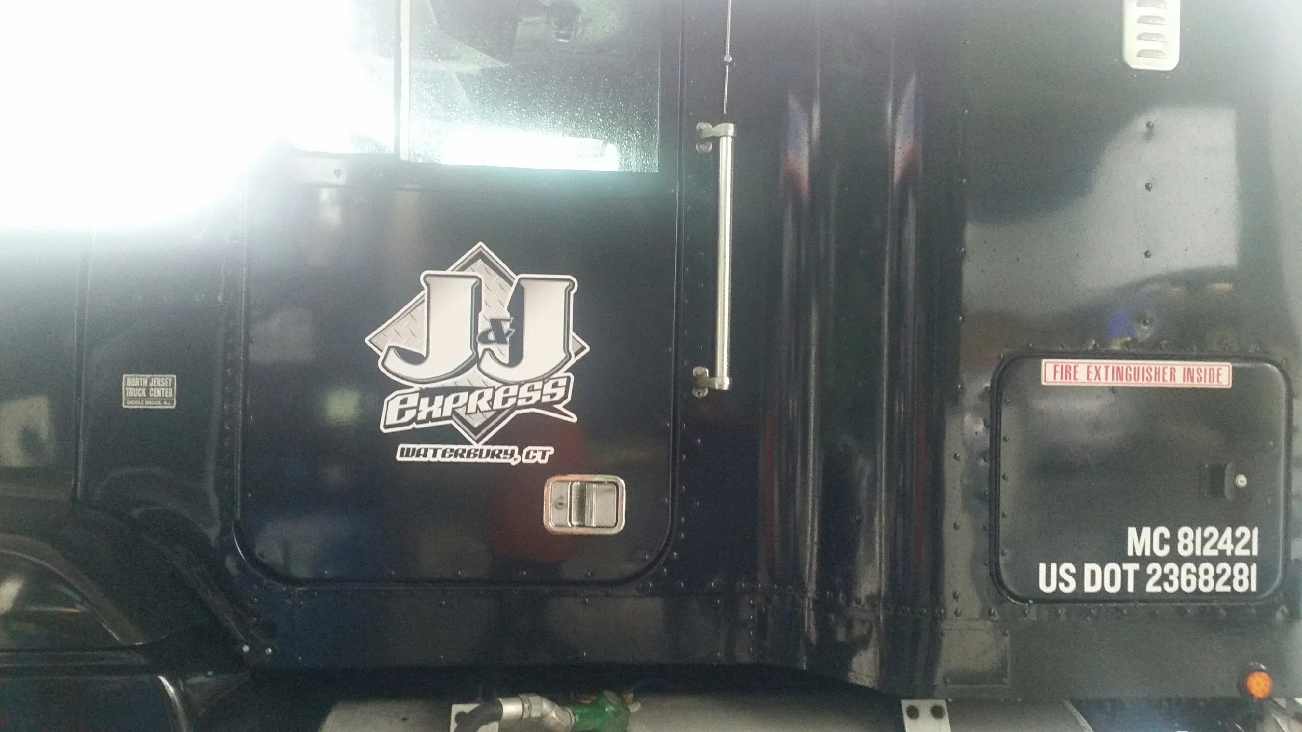 Black truck door featuring a logo with JJ Express and safety information.