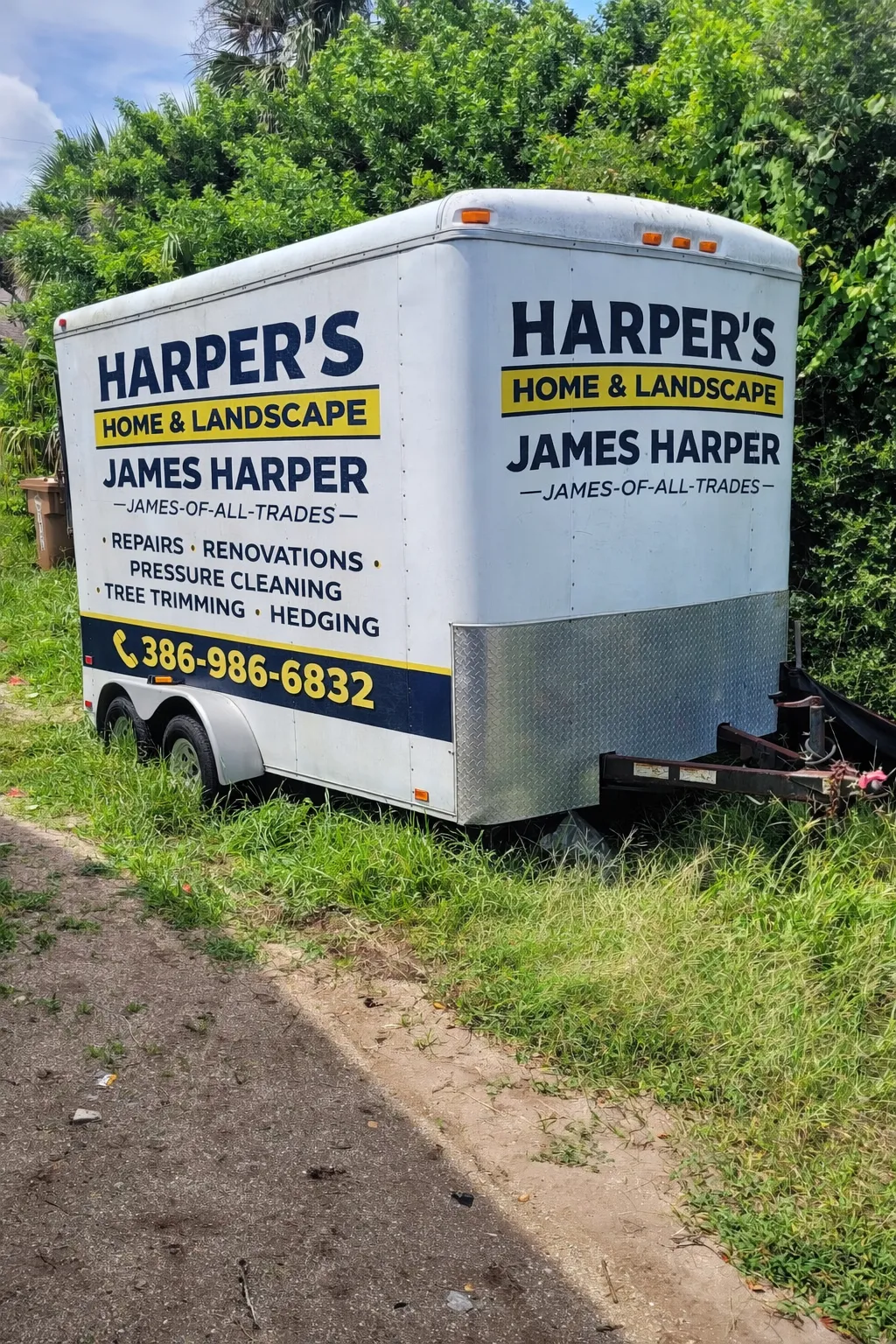 White service trailer lettered with business name, services, and phone number