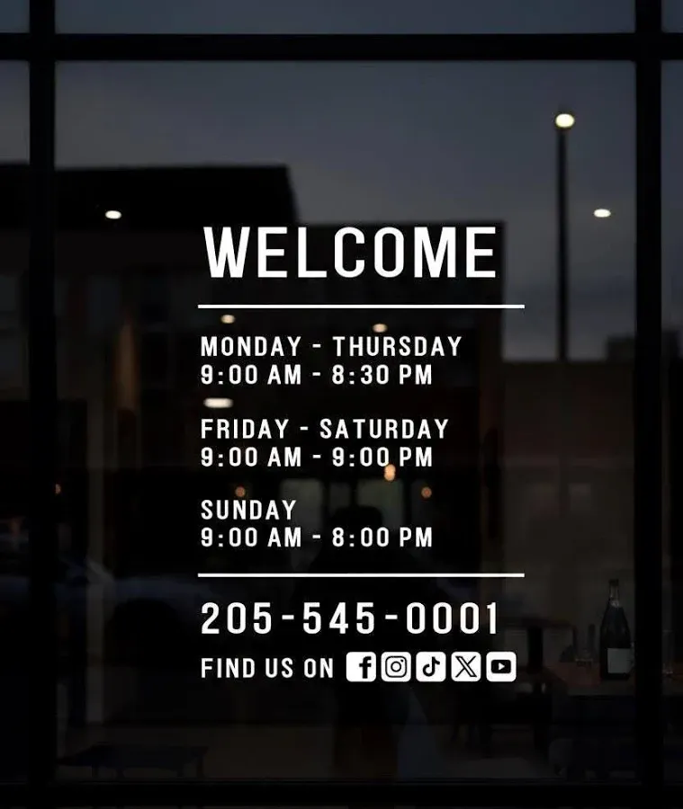 Welcome sign with business hours and contact information on a glass door